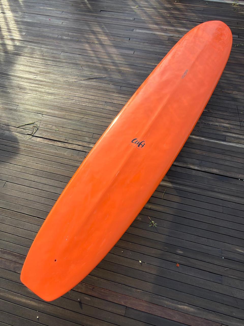 Longboard Lufi One Piece 9'2" seminovo, laranja: prancha inteira pelo fundo, com a caixa de quilha vazia.