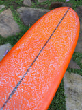 Longboard Lufi One Piece 9'4" seminovo, laranja: bico pelo deck, com a parafina de uso ainda na prancha.