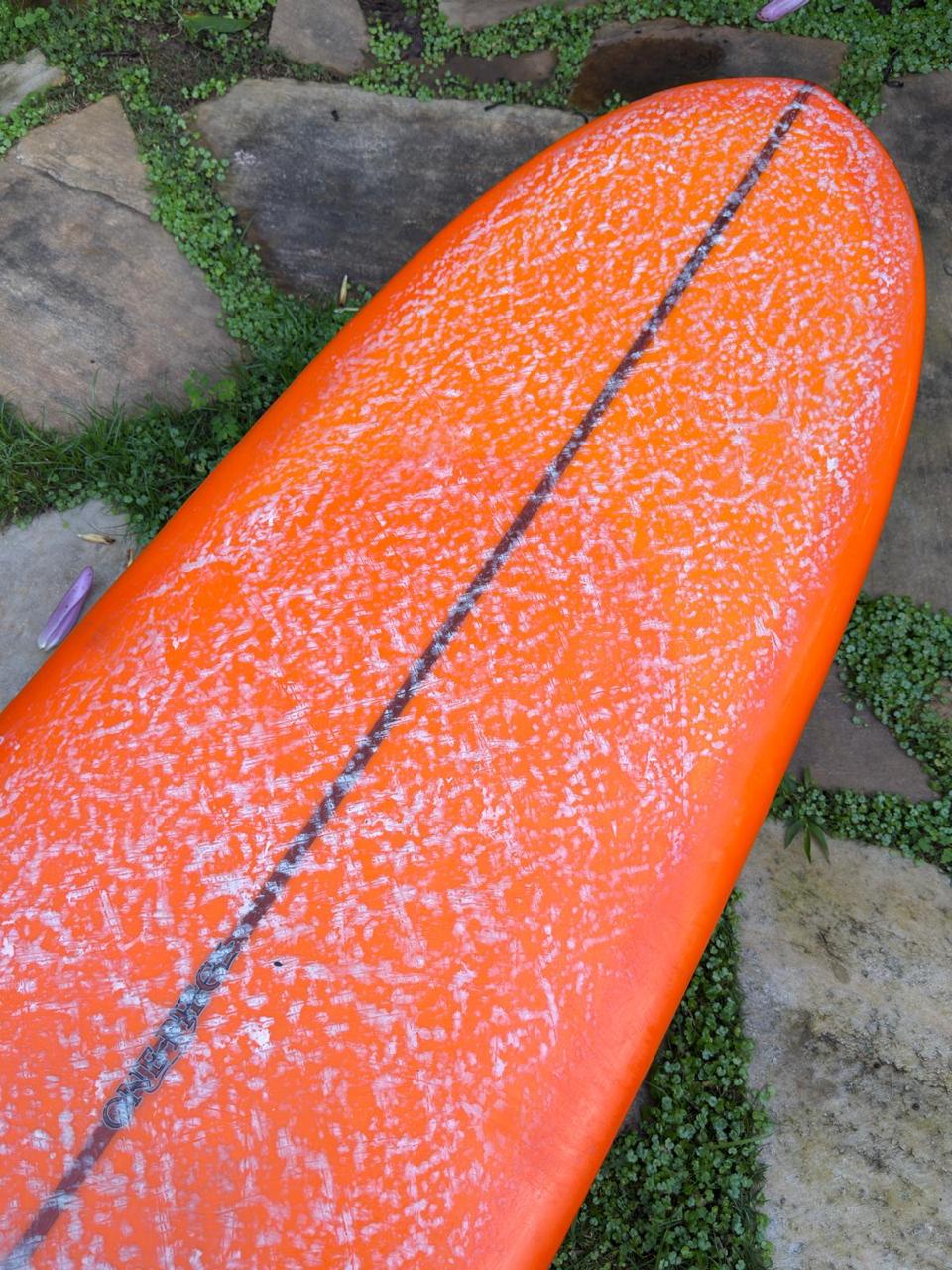 Longboard Lufi One Piece 9'4" seminovo, laranja: bico pelo deck, com a parafina de uso ainda na prancha.