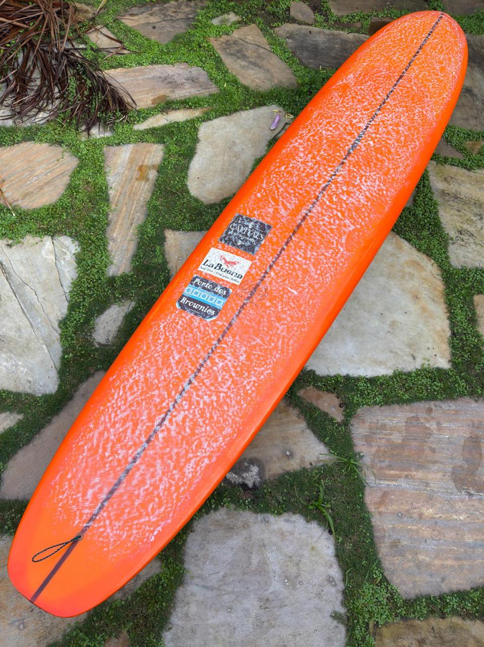 Longboard Lufi One Piece 9'4" seminovo, laranja: prancha inteira pelo deck, com parafina de uso e adesivos do surfista anterior.