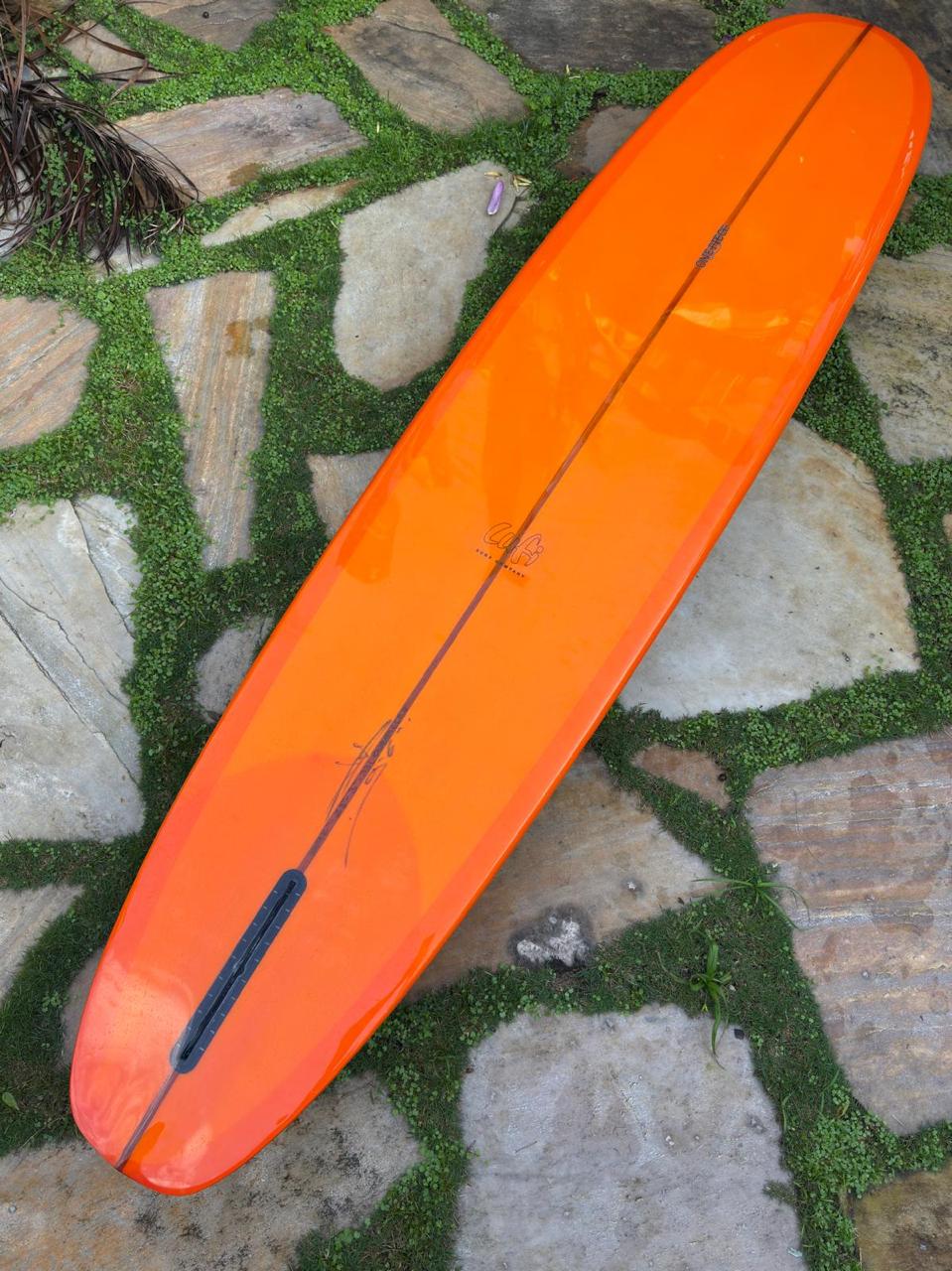 Longboard Lufi One Piece 9'4" seminovo, laranja: prancha inteira pelo fundo, com a caixa de quilha vazia.