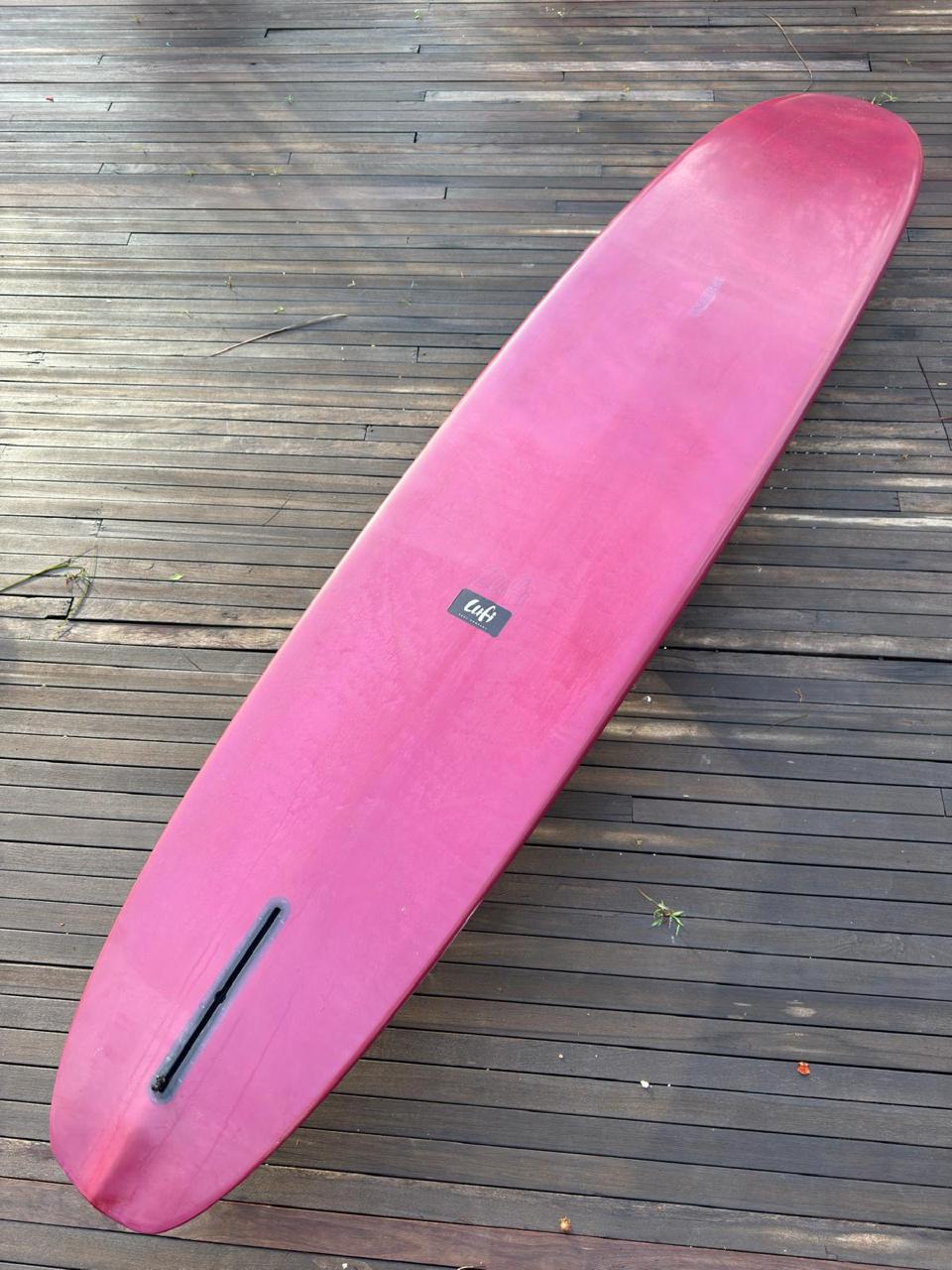 Longboard Lufi One Piece 9'4" seminovo, vinho: prancha inteira pelo fundo, com a caixa de quilha vazia.